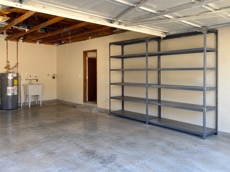 The same garage cleared out, with bare shelves and a swept floor